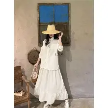 Outfit du lịch biển phong cách tối giản với váy trắng dài, áo sơ mi rộng và mũ cói, phù hợp cho nghỉ dưỡng, dạo biển và chụp ảnh check-in.